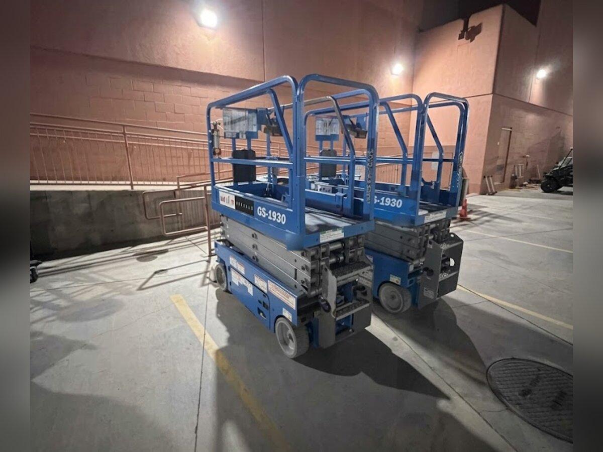 Two Genie GS-1930 19 ft electric scissor lift rentals delivered early in the morning by Summit Rentals to a retail loading area in Chandler, AZ