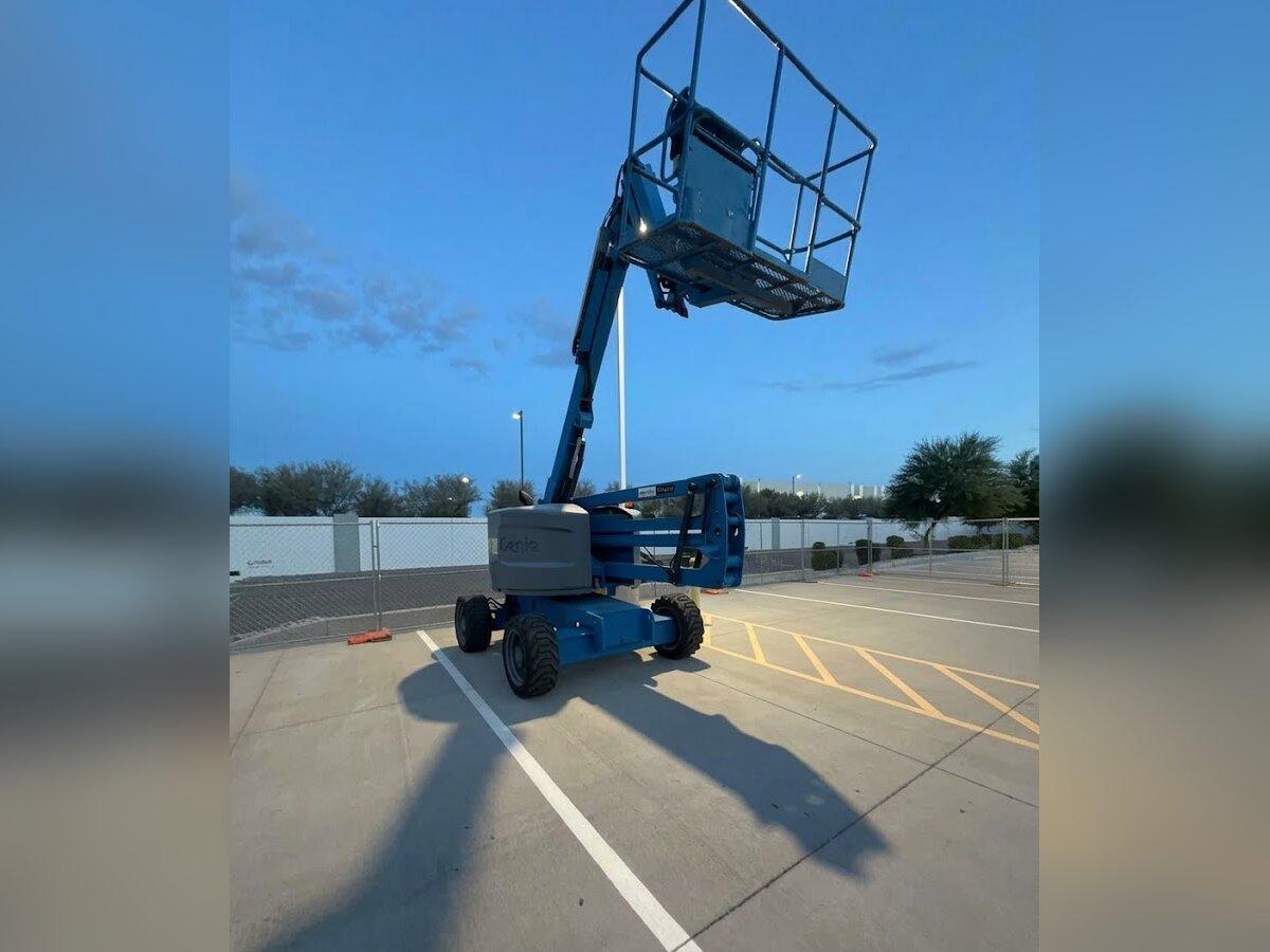 Genie Z-45/25J articulating boom lift with the platform raised, delivered early in the morning by Summit Rentals to a commercial parking lot in Goodyear, AZ