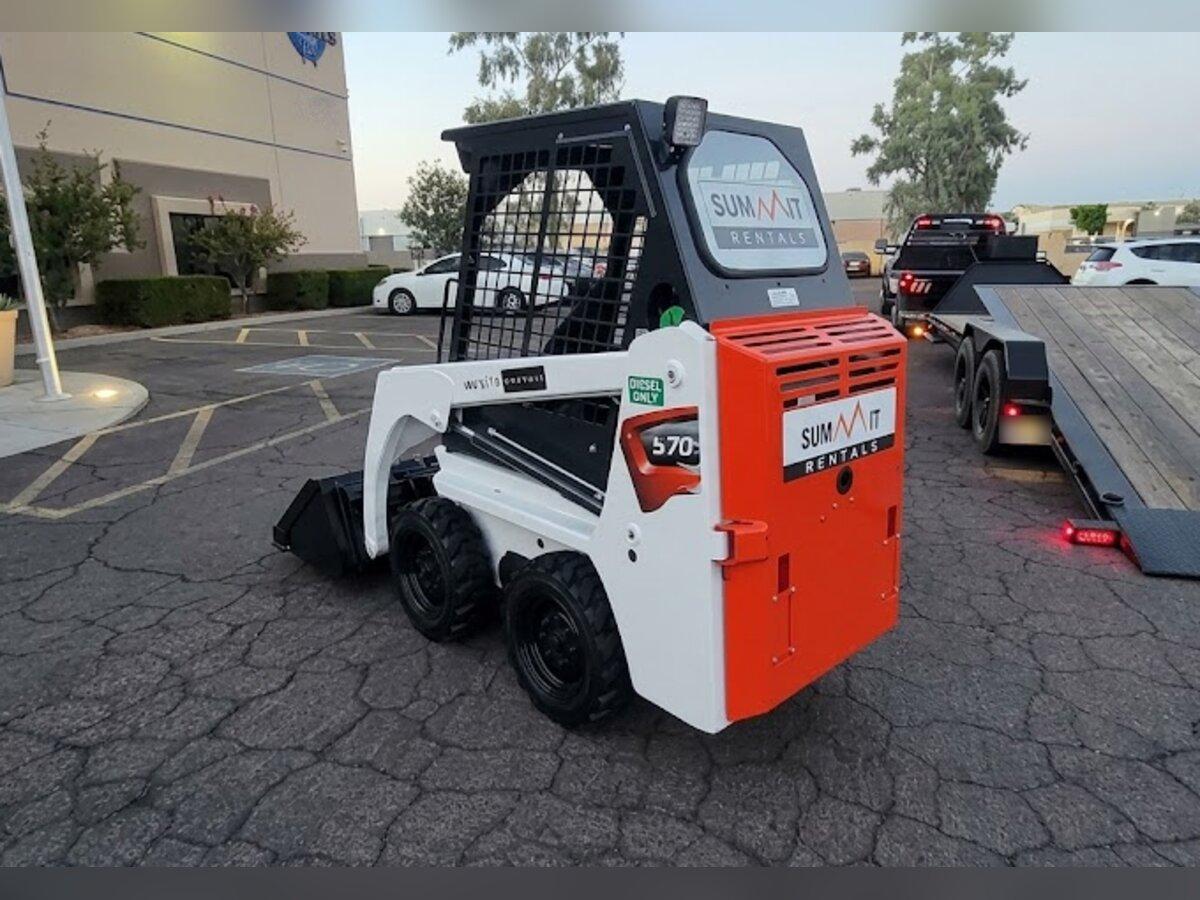 Bobcat S70 700 lb skid steer rental unloaded from a Summit Rentals tilt deck trailer at an office building in Tempe, AZ