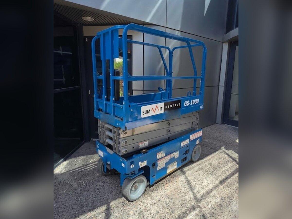 Summit Rentals Genie GS-1930 19 ft electric scissor lift delivered to a modern office building entrance in Tempe, AZ