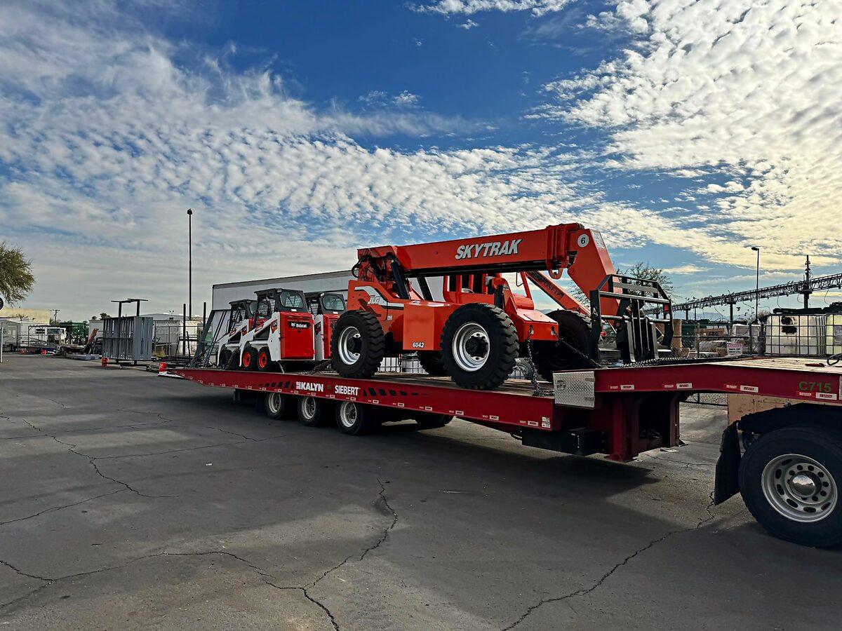 SkyTrak telehandler and Bobcat skid steers on a step deck trailer for delivery across the Phoenix valley