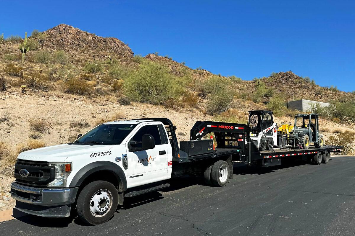 Summit Rentals truck and gooseneck trailer delivering a skid steer and telehandler to a job site in Phoenix, AZ